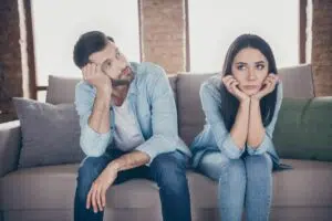 Couple composé d'un homme et d'une femme assis sur un fauteuil et ne se regardant pas, le couple ne semble pas pas complice.